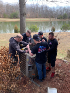 HVAC technicians from Air Solutions Heating and Cooling, LLC. working on an outdoor condenser unit in Louisville, KY.