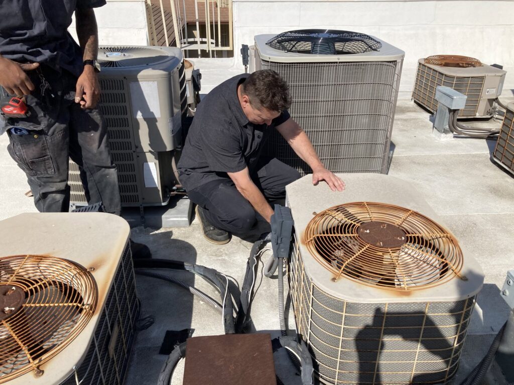 Two HVAC technicians working on multiple commercial rooftop units for Hurn Mechanical Heating & Cooling in El Cajon, CA.