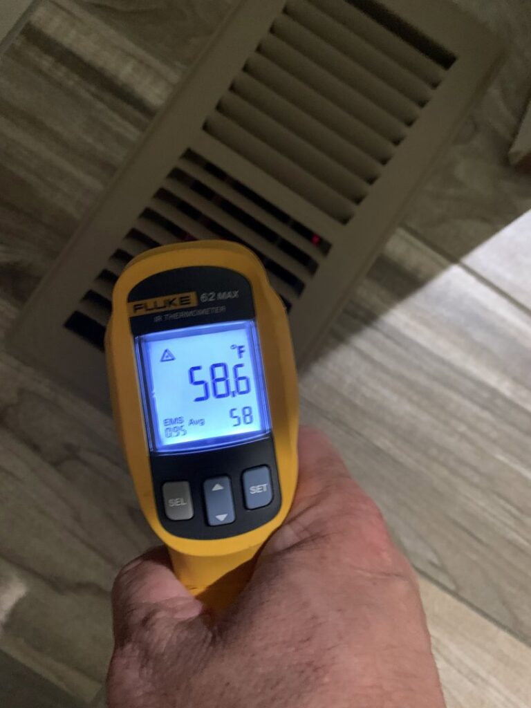 An HVAC technician performing a temperature check at an air vent with an infrared thermometer for U.S. HVAC Services in Madison, AL.