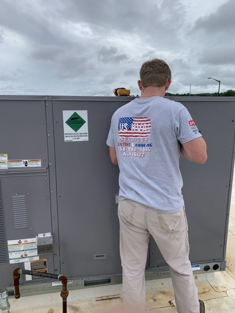 A U.S. HVAC Services, LLC technician checking air vent temperature with an IR thermometer in Madison, AL.