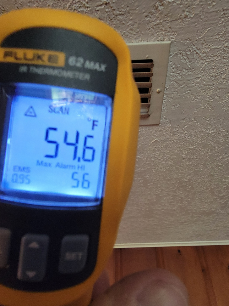 A technician using a Fluke IR thermometer to measure air vent temperature during an HVAC diagnostic by ARKLA AIR LLC in Springhill, LA.