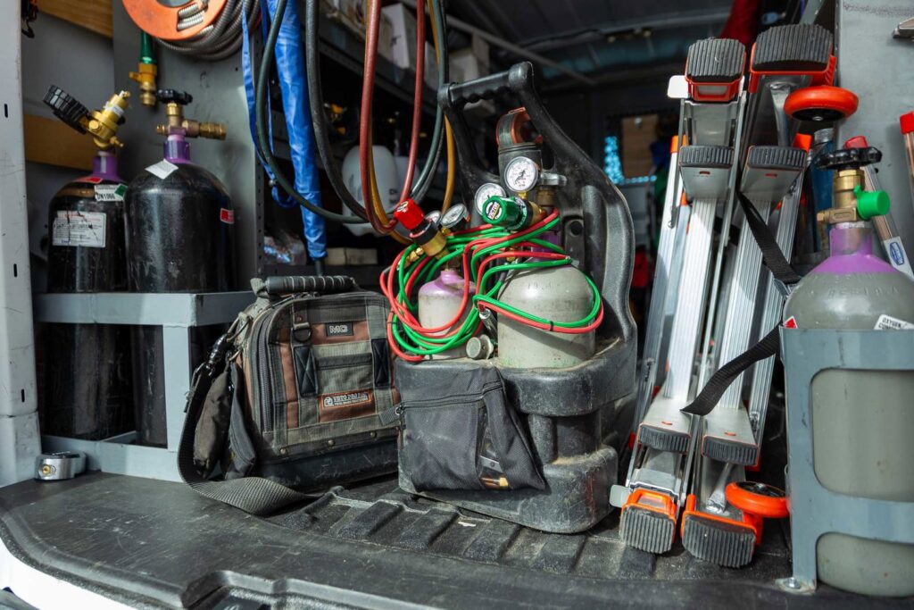 Various HVAC tools, refrigerant tanks, and equipment organized in a service van for AVI Heating & Cooling in Surprise, AZ