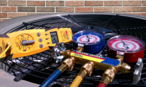 HVAC technician tools, including manifold gauges and a multimeter, resting on an outdoor air conditioning unit at Brudwick Heating & Cooling in Watertown, SD.