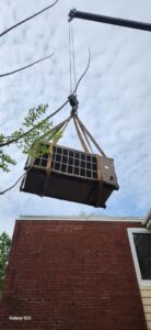 A large outdoor HVAC unit being lifted by a crane during an installation or removal by Cordells Heating and Cooling in Greenville, SC.