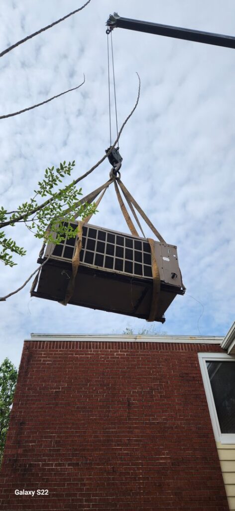 A large outdoor HVAC unit being lifted by a crane during an installation or removal by Cordells Heating and Cooling in Greenville, SC.