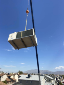 An HVAC unit being carefully lifted by a crane for installation by Aire & Air Heating and Cooling LLC in Las Vegas, NV.