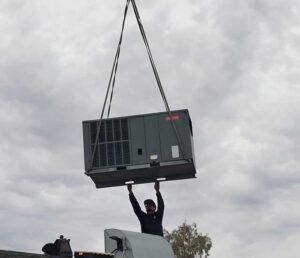 A large HVAC unit being lifted by a crane during installation by Steadfast Mechanical in Gilbert, AZ.