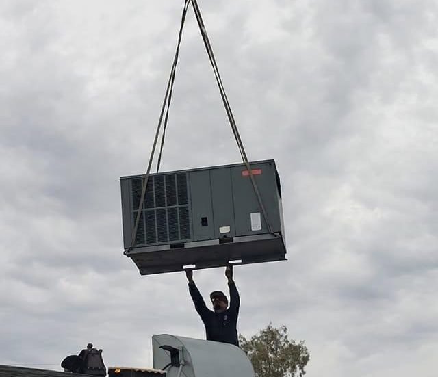 A large HVAC unit being lifted by a crane during installation by Steadfast Mechanical in Gilbert, AZ.