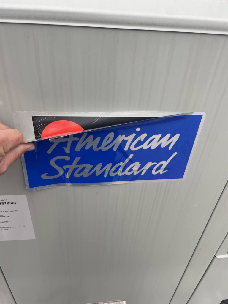 A technician applying branding to a new American Standard HVAC unit during installation by AirWorx - Heating & Cooling in Midvale, UT.