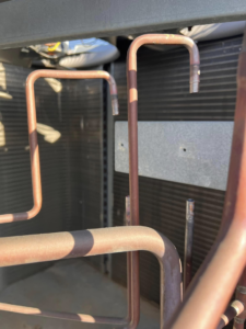 Close-up of copper refrigerant lines and coils inside an HVAC unit, serviced by Mead Heating and Cooling in Kansas City, MO.
