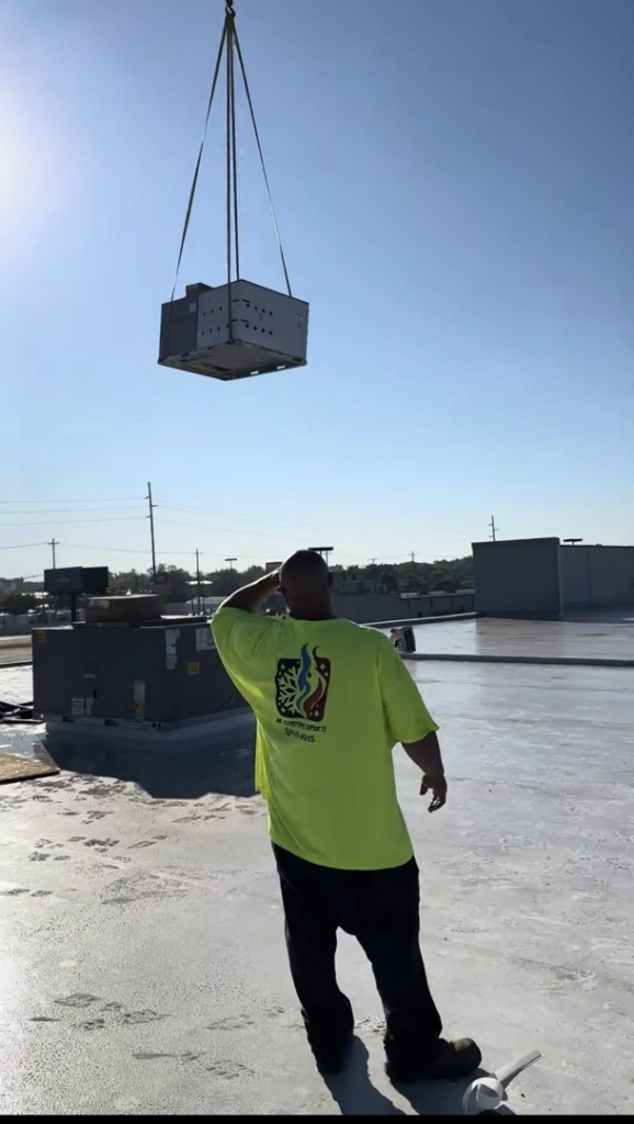 An HVAC technician overseeing a new commercial unit being installed by crane for Air Conditioning Experts in Orlando, FL.