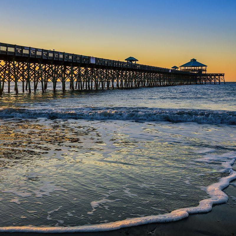 A Burke Services, Inc. technician overseeing an HVAC unit installation with a crane at a property in Folly Beach, SC.