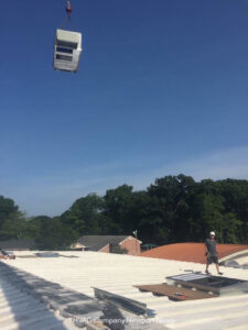 A large HVAC unit being lifted by a crane onto a commercial rooftop for installation by Cannon Heating and Air Conditioning, LLC in Newport News, VA.