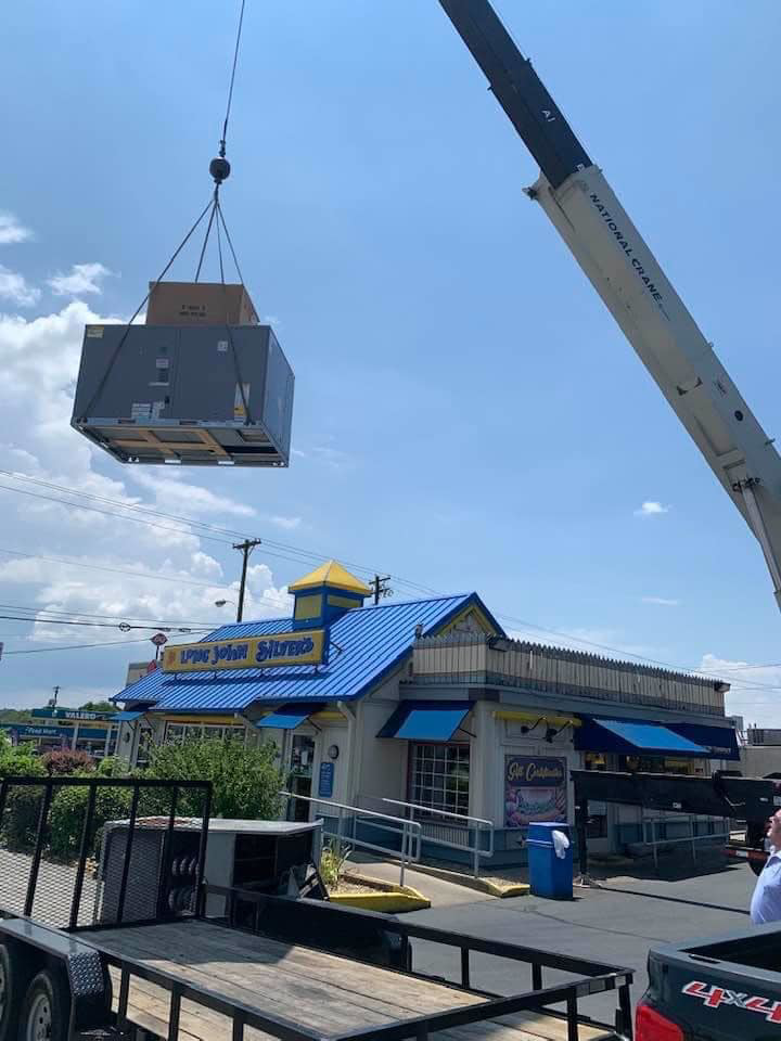 A large HVAC unit being lifted by a crane for installation at a commercial building by Lexington Mechanical Service in Lexington, KY.