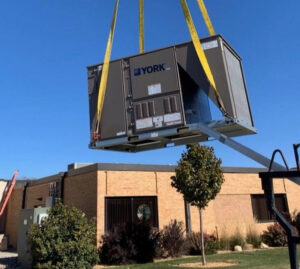 A new York HVAC unit being lifted by a crane for installation by Schomp's Mechanical Services in Brookings, SD.