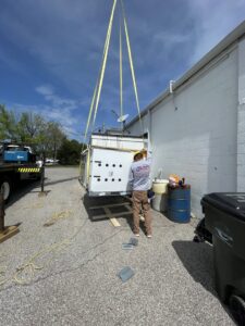 A large HVAC unit being lifted by a crane for installation by Wes-Tech Services in Bloomington, IN.
