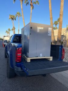 HVAC technicians using a crane to lift a new unit onto a rooftop for installation by Klee's Climate Control in Mesa, AZ.