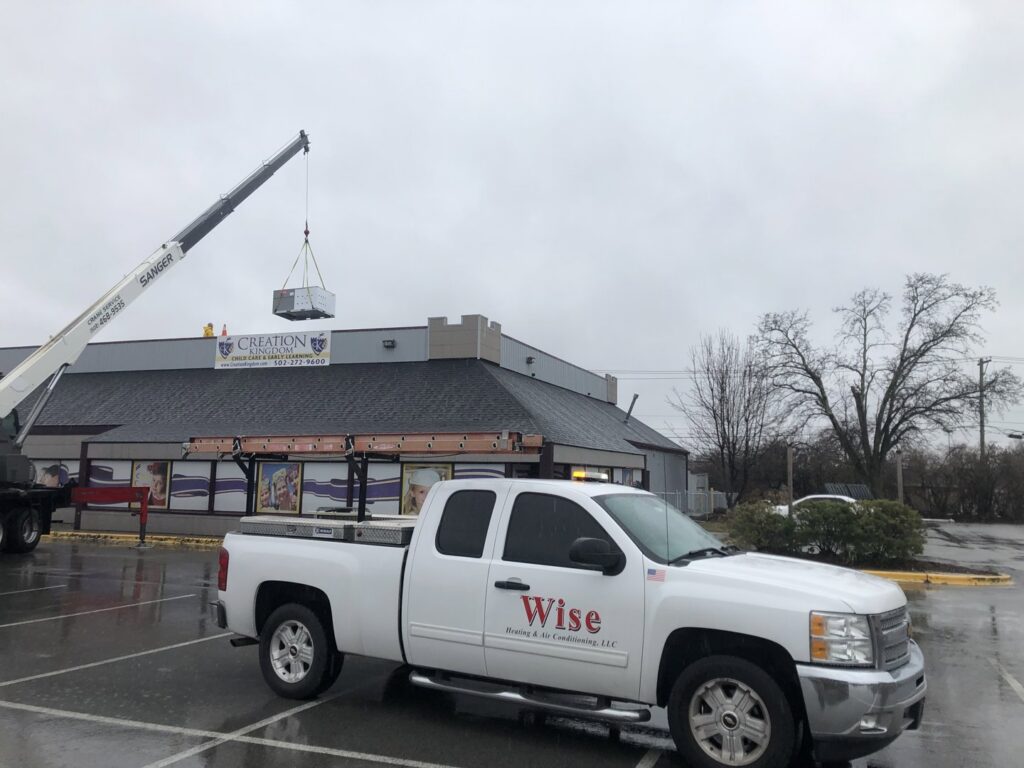 A crane lifting an HVAC unit onto a rooftop during an installation by Wise Heating & Air Conditioning, LLC in Louisville, KY.