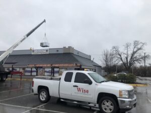 A crane lifting an HVAC unit onto a rooftop during an installation by Wise Heating & Air Conditioning, LLC in Louisville, KY.