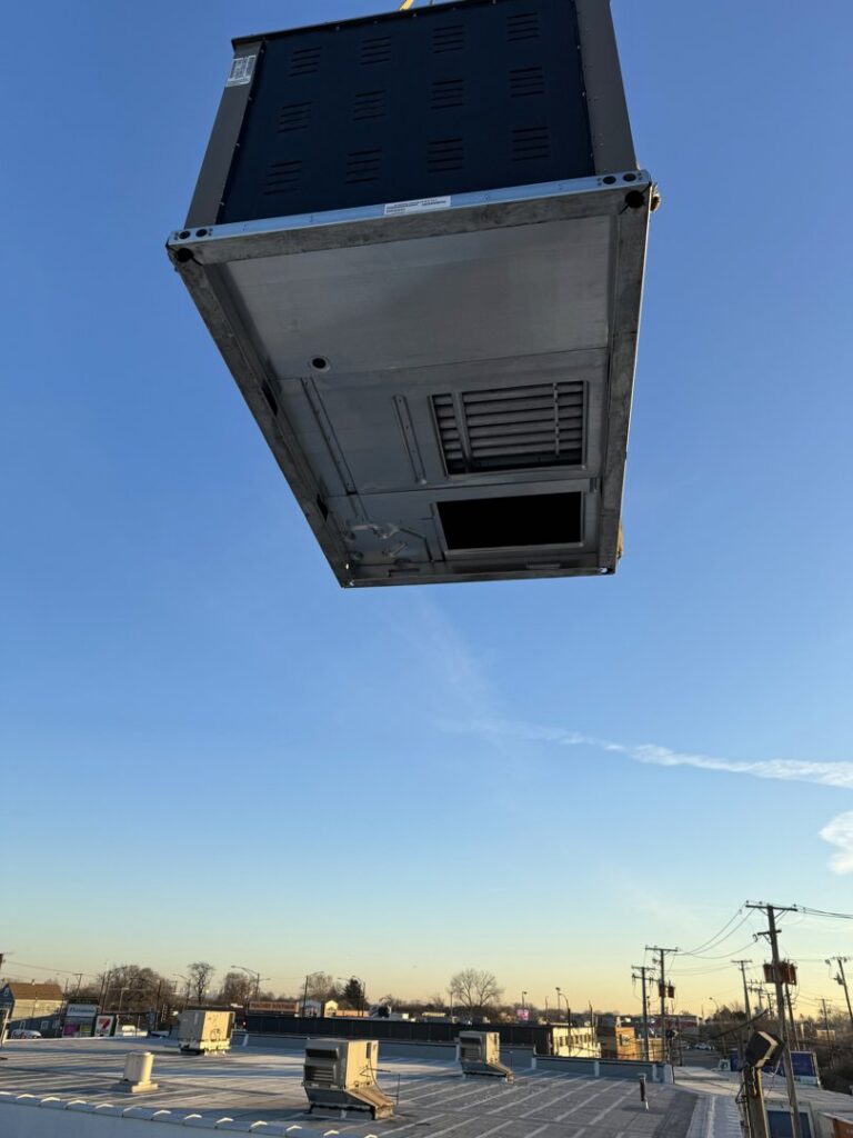A large HVAC unit being lifted by a crane for rooftop installation by Etek Refrigeration Heating and Cooling, Inc. in Chicago, IL.
