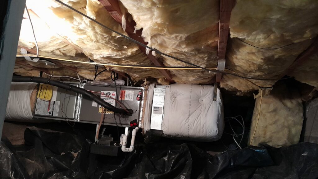 An HVAC air handler unit installed in a crawl space or attic, surrounded by insulation, by PNW Spokane Heating and Air in Spokane, WA.