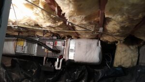An HVAC air handler unit installed in a crawl space or attic, surrounded by insulation, by PNW Spokane Heating and Air in Spokane, WA.