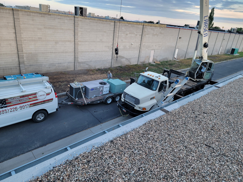 A crane and service van delivering large HVAC units for installation by Carter HVAC & Service in Seagrove, NC.