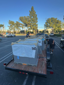 Rosales Aire Inc. technicians unloading new HVAC units from a trailer for an installation project in Anaheim, CA.
