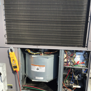 An HVAC technician performing diagnostic and repair work on an outdoor unit with a multimeter for KAP'S HVAC in Portland, OR.
