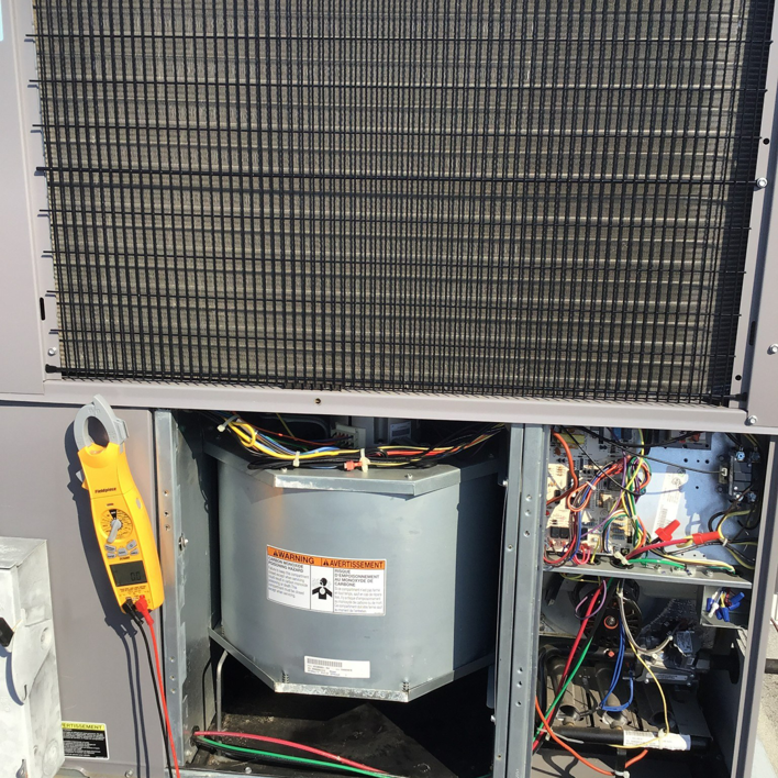 An HVAC technician performing diagnostic and repair work on an outdoor unit with a multimeter for KAP'S HVAC in Portland, OR.