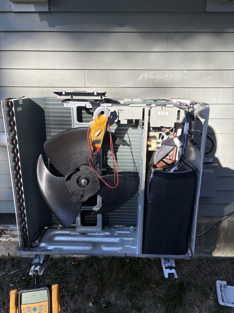 An HVAC technician performing diagnostic and repair service on an outdoor unit with a multimeter by Laird's HVAC in Auburn, ME.