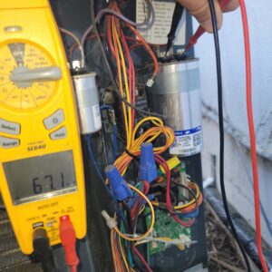 A technician performing electrical diagnostics on an outdoor HVAC unit with a multimeter for Ecology Air Innovations in Sacramento, CA.