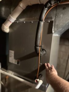A technician's hand pointing to an HVAC unit during an inspection or service by Trade Allies Heating and Cooling in Ankeny, IA.