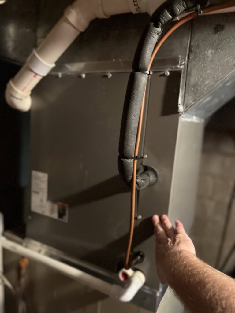 A technician's hand pointing to an HVAC unit during an inspection or service by Trade Allies Heating and Cooling in Ankeny, IA.