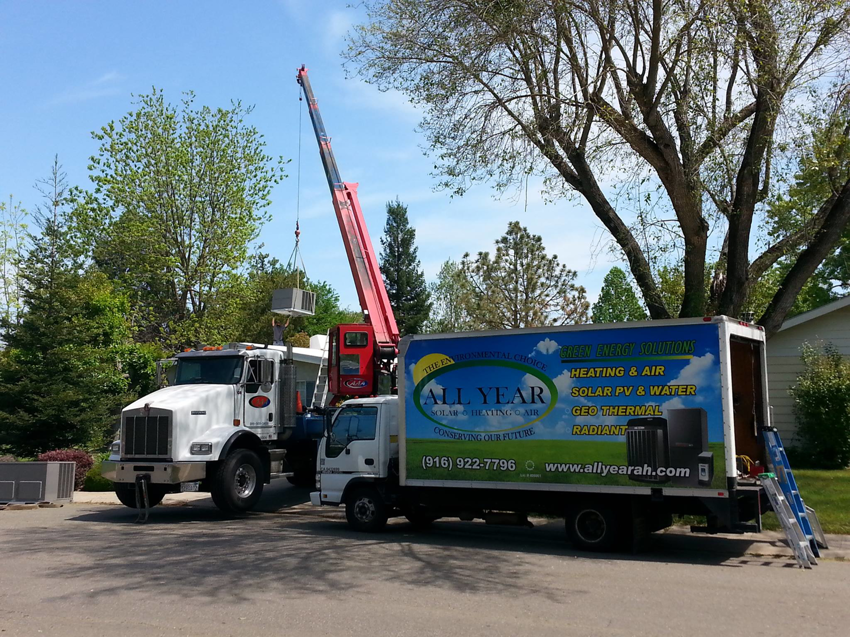 A crane lifting a new HVAC unit onto a roof for installation by ALL YEAR Heating, Air and Solar in Sacramento, CA.