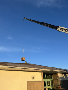 A crane lifting an HVAC unit onto a rooftop during installation by Atlas Heating and Air, LLC in Talent, OR