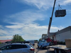A crane lifts a new HVAC unit onto a commercial building roof for installation by Comfort Systems USA Temp Right Service in Kalispell, MT.