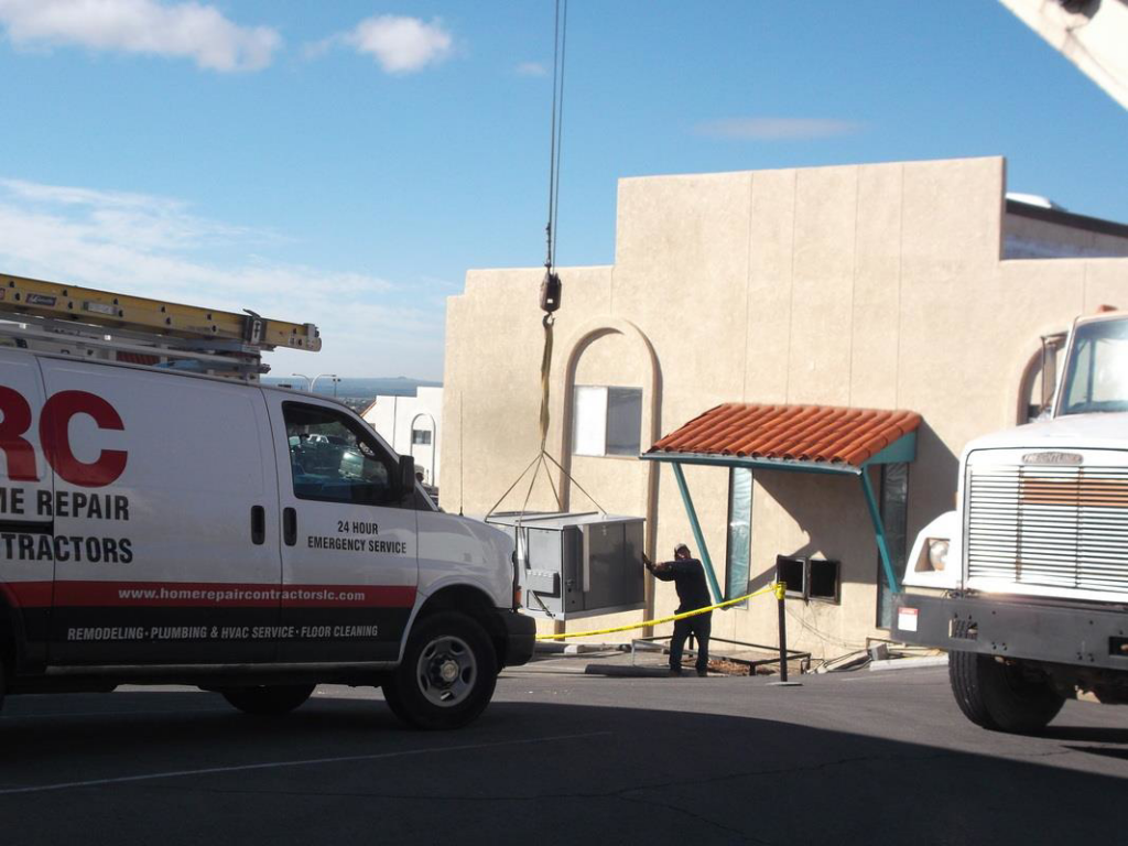 A large HVAC unit being installed by a crane at a commercial building by Home Repair Contractors in Las Cruces, NM