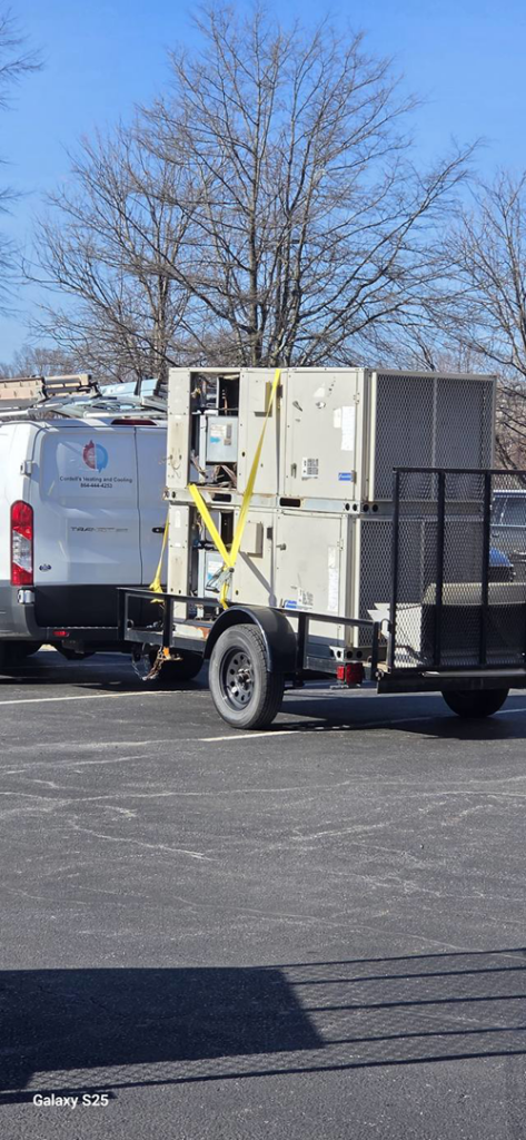 An HVAC unit on a trailer with a Cordells Heating and Cooling service van in the background in Greenville, SC.