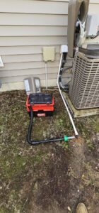 An outdoor HVAC unit connected to a vacuum pump for refrigerant service by Peak Seasons HVAC in Raleigh, NC.