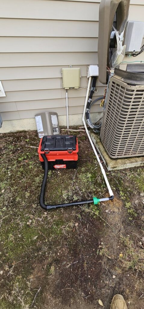 An outdoor HVAC unit connected to a vacuum pump for refrigerant service by Peak Seasons HVAC in Raleigh, NC.