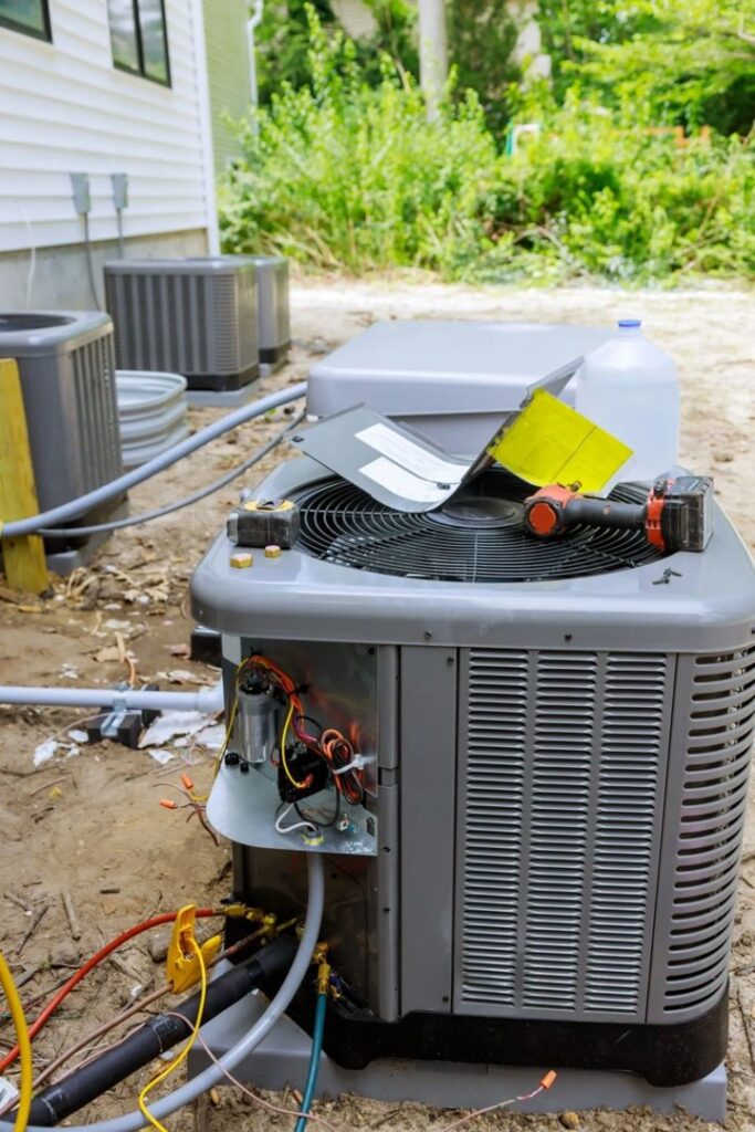 An outdoor HVAC unit undergoing repair or maintenance with tools and wiring visible by Ault's Cooling HVAC Services LLC in Chandler, AZ.