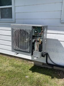 An outdoor HVAC unit with its side panel open, revealing internal components during a service or repair by DeltaCool in Jonesboro, AR.