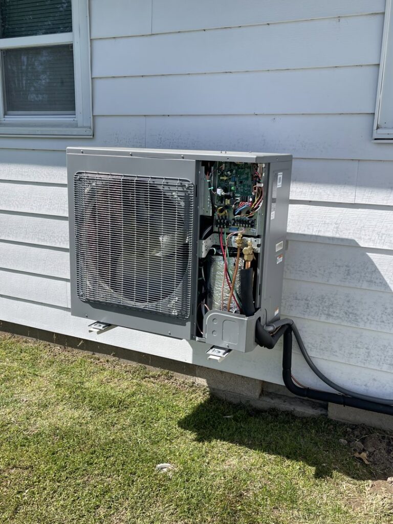 An outdoor HVAC unit with its side panel open, revealing internal components during a service or repair by DeltaCool in Jonesboro, AR.