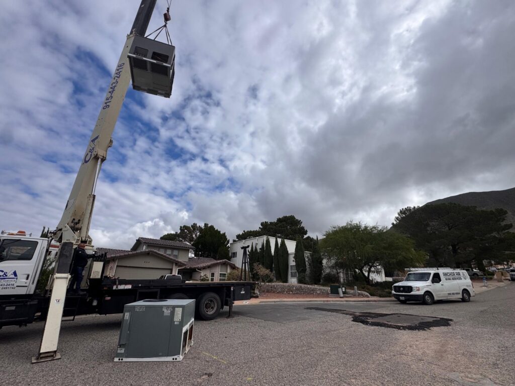 An HVAC unit replacement in progress with a crane and Anchor Air service van on site in El Paso, TX