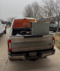 A Freedom Heating & Cooling truck transporting an HVAC unit in Lathrop, MO, ready for installation or removal.