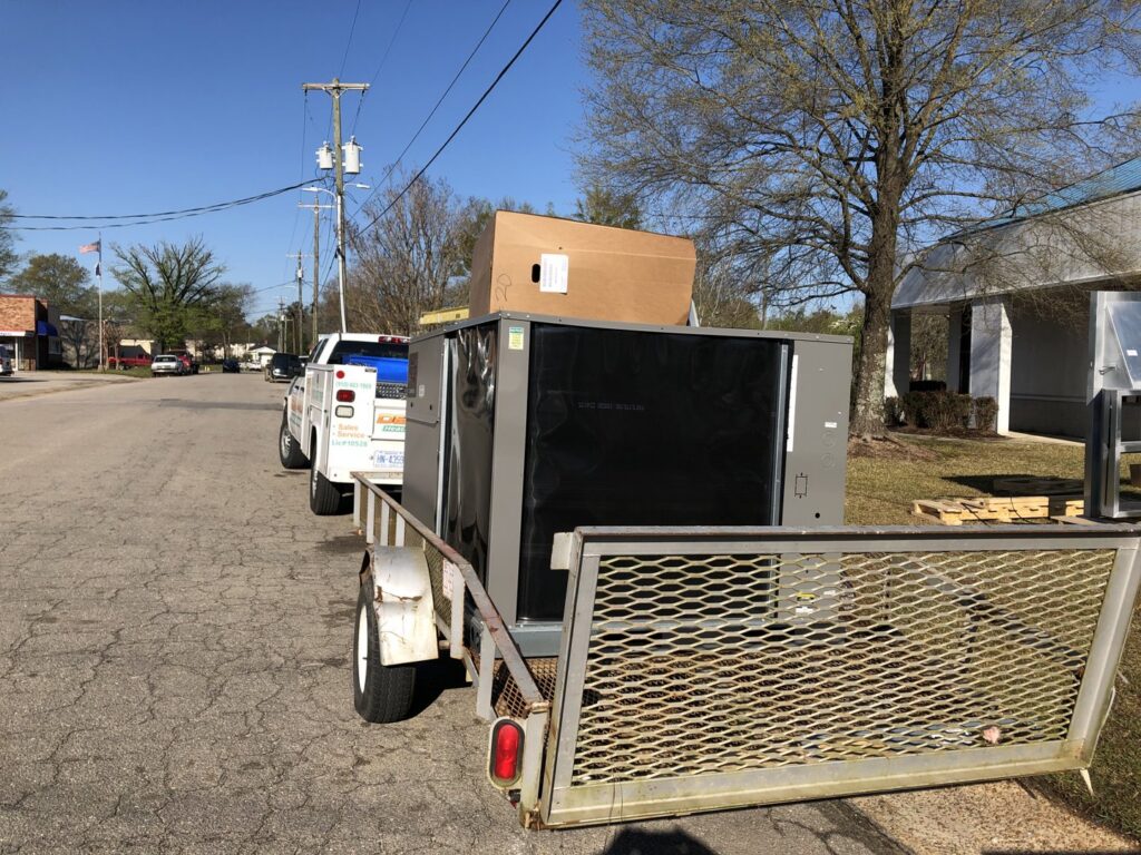 A new HVAC unit being transported on a trailer by Deon Arnold Heating & Air Conditioning in Fayetteville, NC