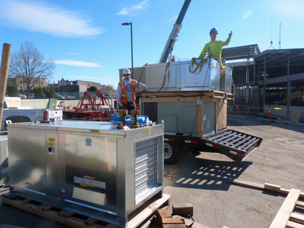 R&R Heating & Air Conditioning workers delivering and preparing HVAC units for installation at a construction site in Spokane, WA.