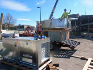 R&R Heating & Air Conditioning workers delivering and preparing HVAC units for installation at a construction site in Spokane, WA.