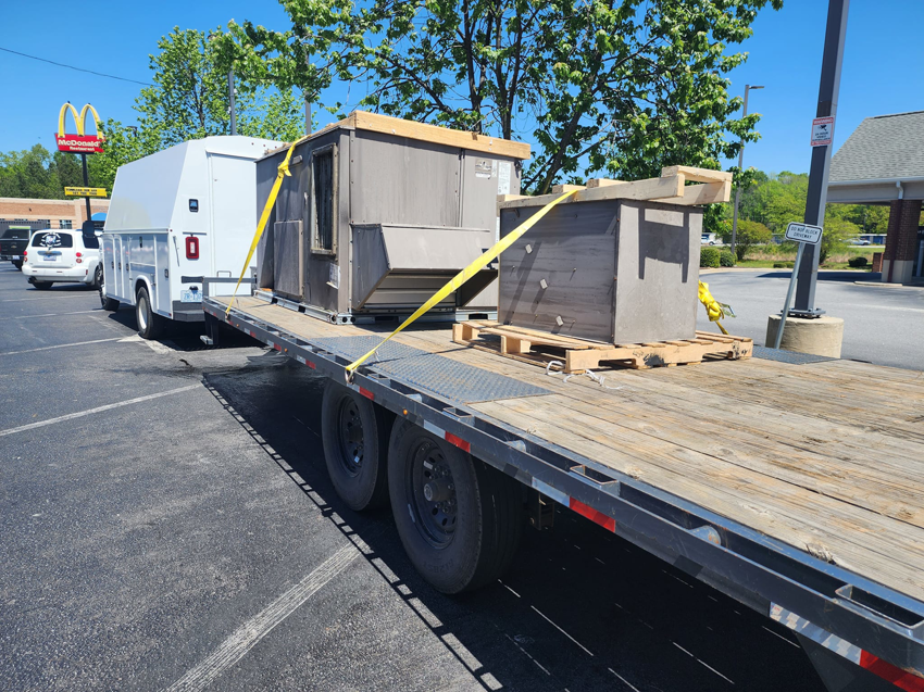 Large HVAC units being transported on a trailer for installation by Facility Doctors in Raleigh, NC
